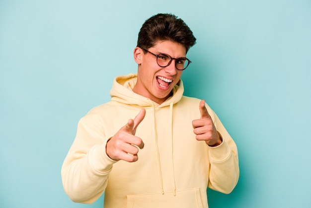 Young caucasian man isolated on blue background pointing to front with fingers