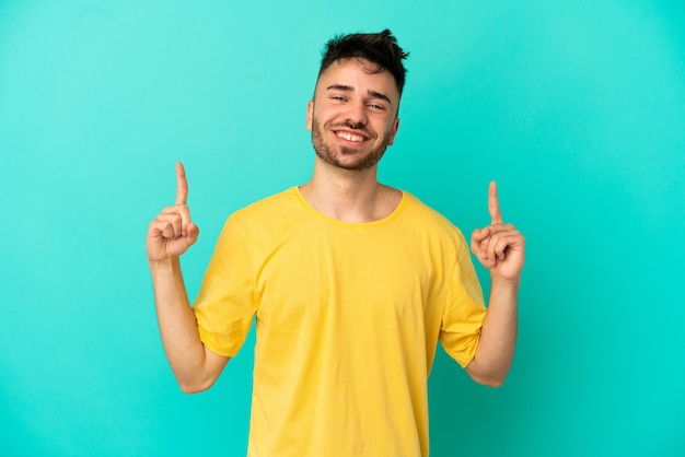 Young caucasian man isolated on blue background pointing up a great idea