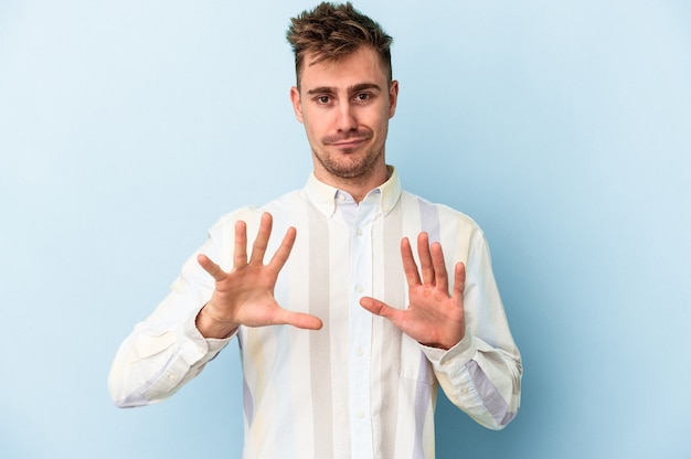 Young caucasian man isolated on blue background rejecting someone showing a gesture of disgust.