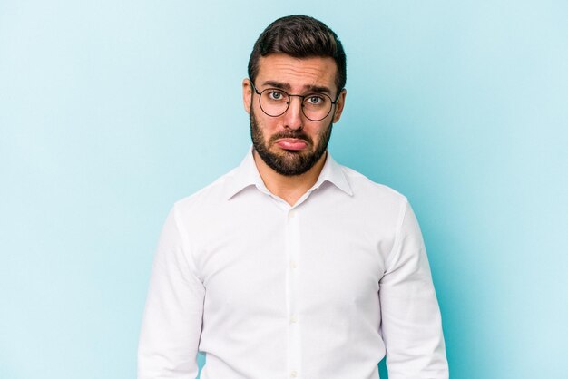 Young caucasian man isolated on blue background sad serious face feeling miserable and displeased