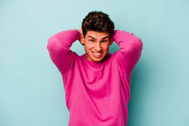 Young caucasian man isolated on blue background screaming with rage