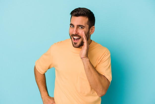 Young caucasian man isolated on blue background shouting excited to front.