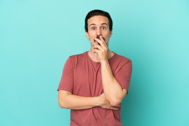 Young caucasian man isolated on blue background surprised and shocked while looking right