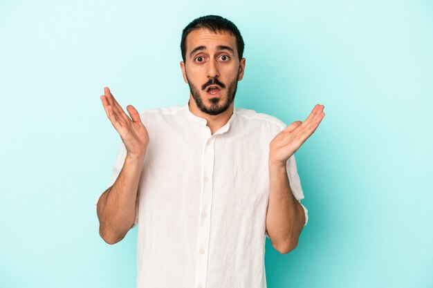 Young caucasian man isolated on blue background surprised and shocked.