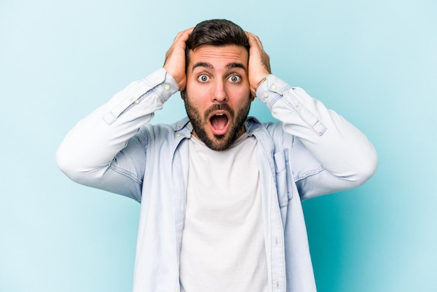 Young caucasian man isolated on blue background surprised and shocked