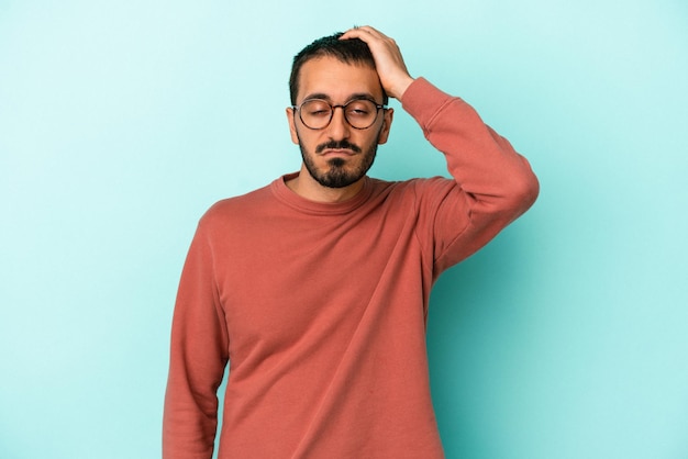 Young caucasian man isolated on blue background tired and very sleepy keeping hand on head.