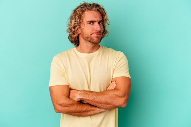 Young caucasian man isolated on blue background unhappy looking in camera with sarcastic expression.