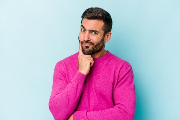 Young caucasian man isolated on blue background unhappy looking in camera with sarcastic expression