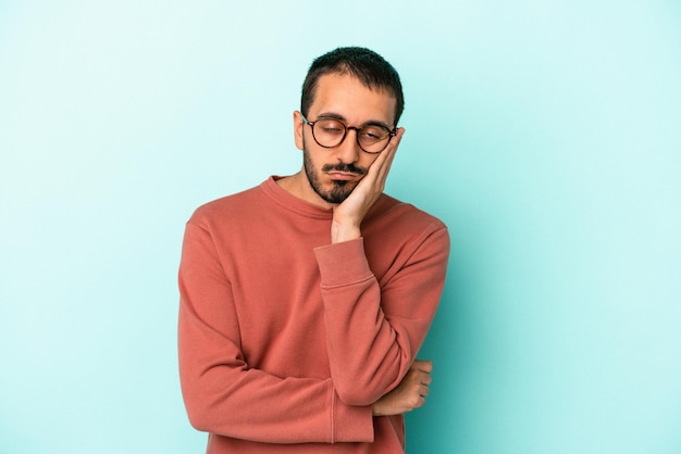 Young caucasian man isolated on blue background who is bored fatigued and need a relax day