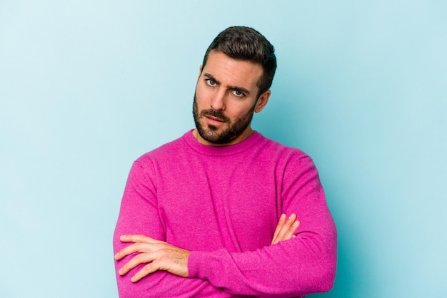 Young caucasian man isolated on blue background who is bored fatigued and need a relax day