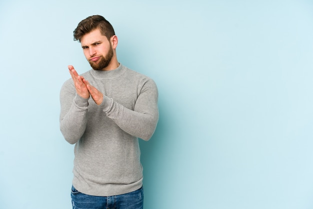 Young caucasian man isolated on blue feeling energetic and comfortable, rubbing hands confident.