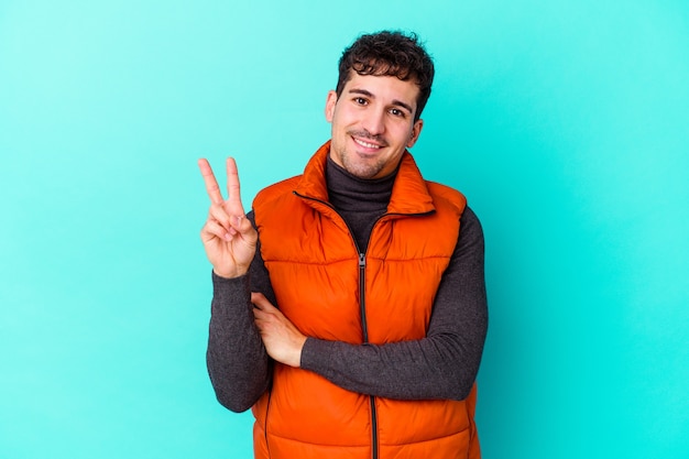 Young caucasian man isolated on blue showing number two with fingers.