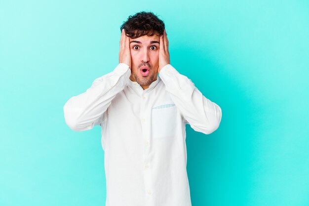 Young caucasian man isolated on blue wall being shocked, she has remembered important meeting.