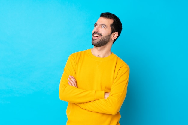 Young caucasian man over isolated blue wall happy and smiling