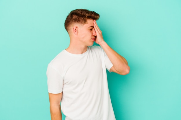 Giovane uomo caucasico isolato sulla parete blu con mal di testa, toccando la parte anteriore del viso
