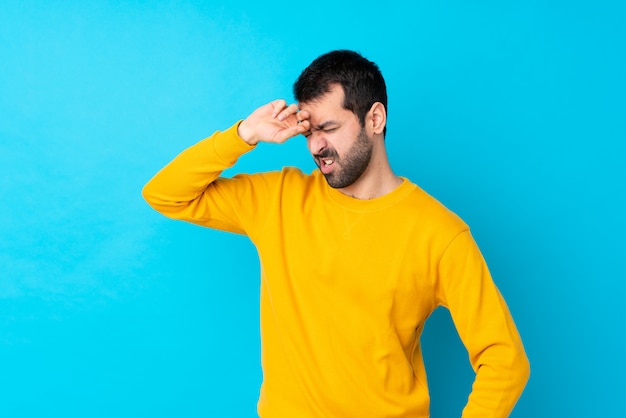 Young caucasian man over isolated blue wall with tired and sick expression