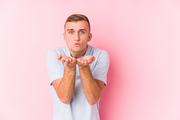 Young caucasian man isolated folding lips and holding palms to send air kiss.