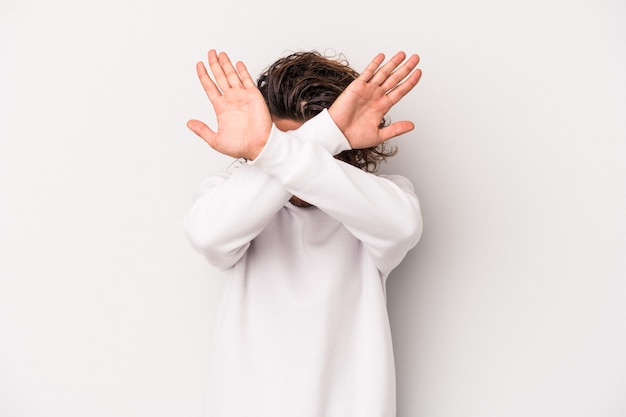 Young caucasian man isolated on gray background keeping two arms crossed, denial concept.