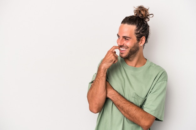 Young caucasian man isolated on gray background relaxed thinking about something looking at a copy space.