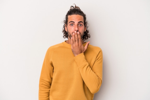 Young caucasian man isolated on gray background shocked, covering mouth with hands, anxious to discover something new.