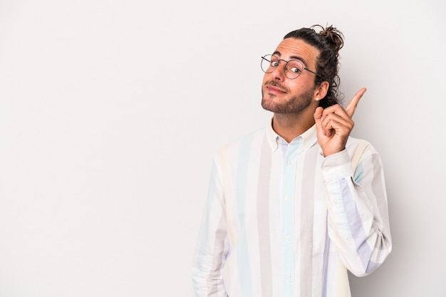 Young caucasian man isolated on gray background showing number one with finger.