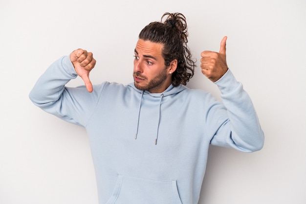 Young caucasian man isolated on gray background showing thumbs up and thumbs down, difficult choose concept