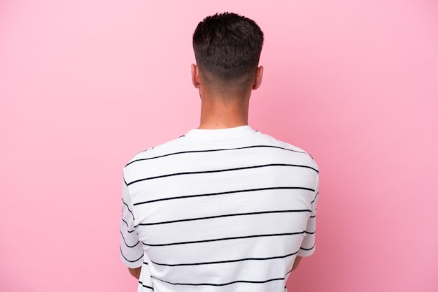 Photo young caucasian man isolated on pink background in back position