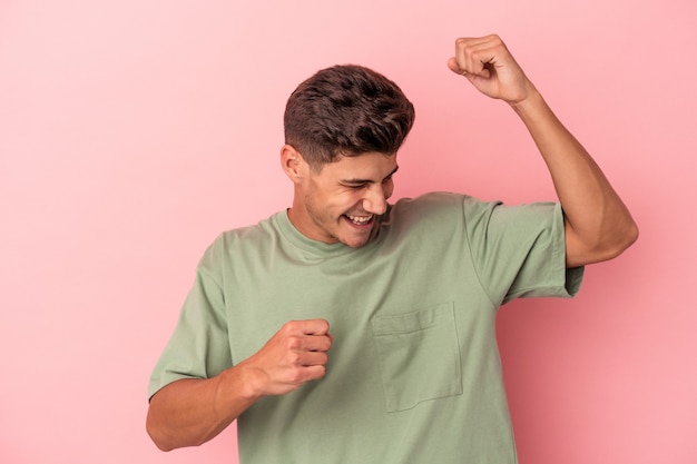 Young caucasian man isolated on pink background dancing and having fun.