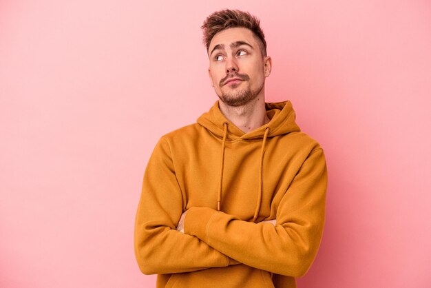 Young caucasian man isolated on pink background dreaming of achieving goals and purposes