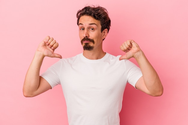 Young caucasian man isolated on pink background feels proud and self confident, example to follow.