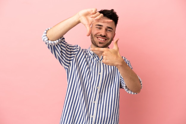 Young caucasian man isolated on pink background focusing face. Framing symbol