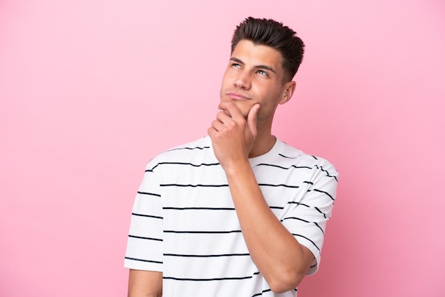 Young caucasian man isolated on pink background and looking up