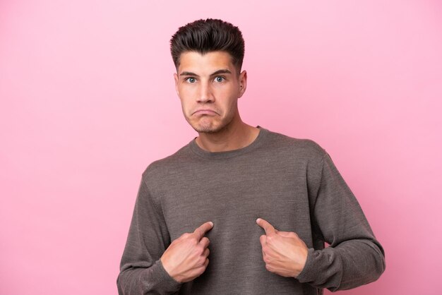 Young caucasian man isolated on pink background pointing to oneself