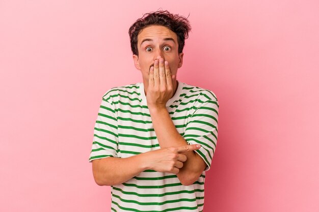 Young caucasian man isolated on pink background pointing to the side