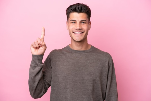 Young caucasian man isolated on pink background pointing up a great idea