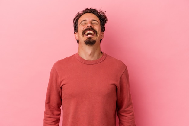 Young caucasian man isolated on pink background relaxed and happy laughing, neck stretched showing teeth.