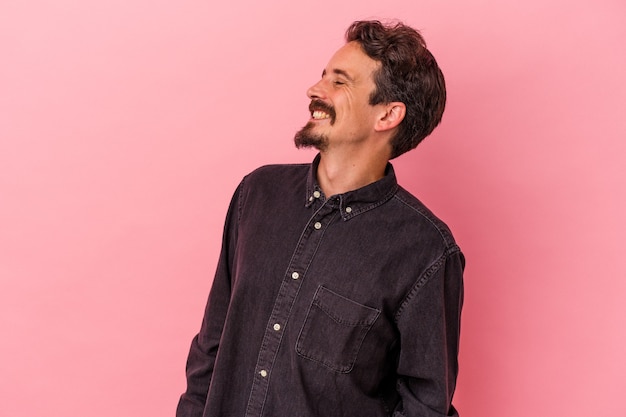 Young caucasian man isolated on pink background relaxed and happy laughing, neck stretched showing teeth.