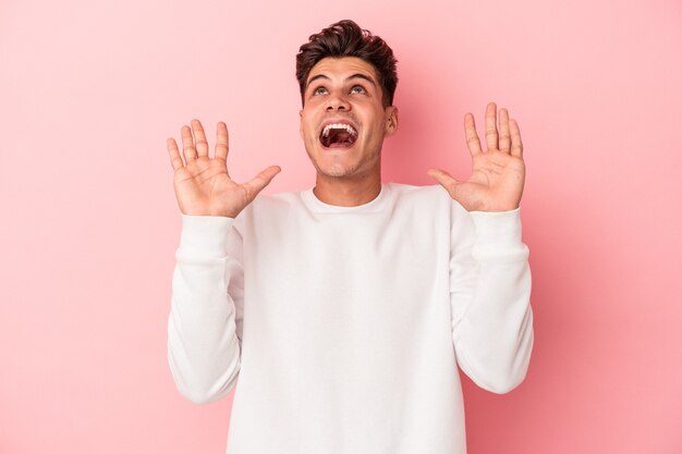 Young caucasian man isolated on pink background screaming to the sky, looking up, frustrated.