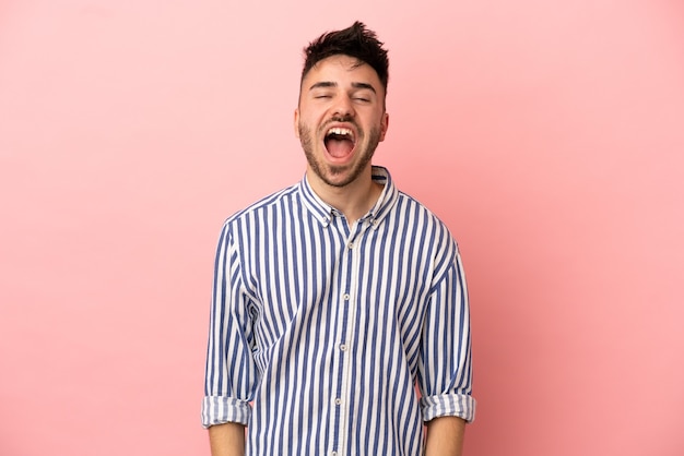 Young caucasian man isolated on pink background shouting to the front with mouth wide open