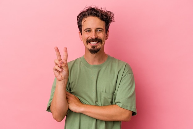 Young caucasian man isolated on pink background showing number two with fingers.