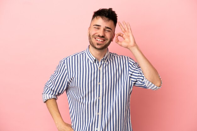 Young caucasian man isolated on pink background showing ok sign with fingers