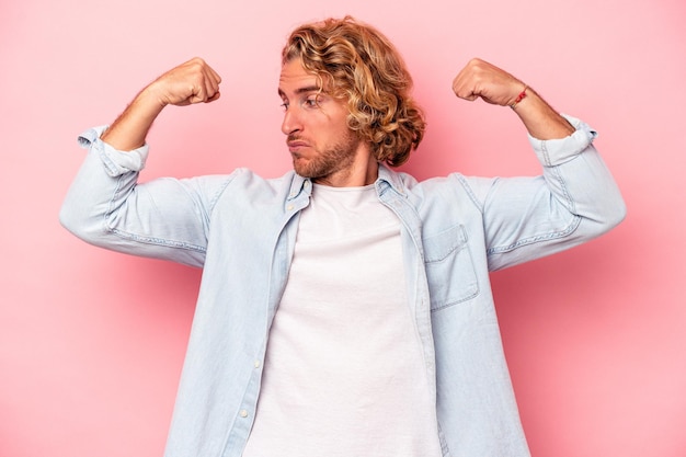 Photo young caucasian man isolated on pink background showing strength gesture with arms, symbol of feminine power