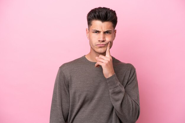 Young caucasian man isolated on pink background and thinking