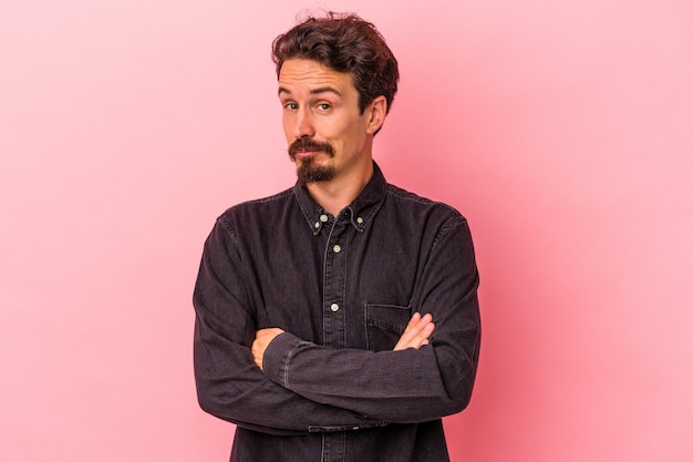 Young caucasian man isolated on pink background unhappy looking in camera with sarcastic expression.