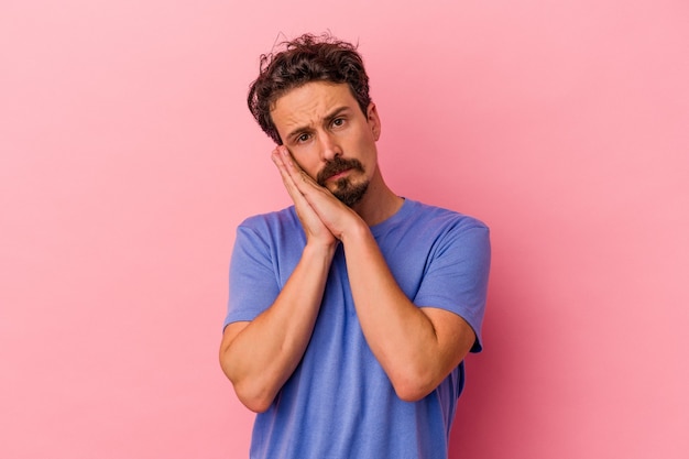 Young caucasian man isolated on pink background yawning showing a tired gesture covering mouth with hand.