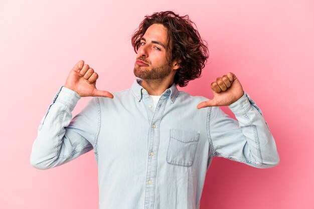 Young caucasian man isolated on pink bakcground feels proud and self confident, example to follow.