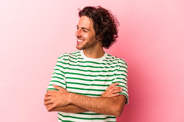 Young caucasian man isolated on pink bakcground smiling confident with crossed arms.