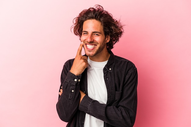 Young caucasian man isolated on pink bakcground smiling happy and confident, touching chin with hand.