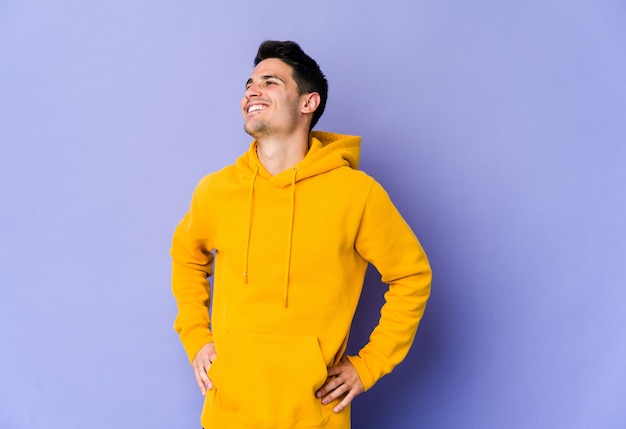 Young caucasian man isolated on purple background relaxed and happy laughing, neck stretched showing teeth.