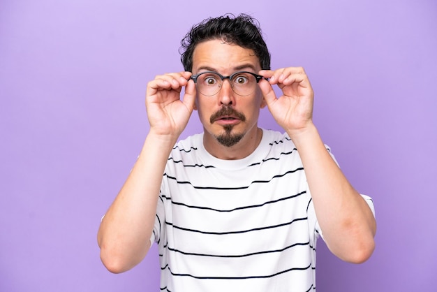 Young caucasian man isolated on purple background With glasses and frustrated expression